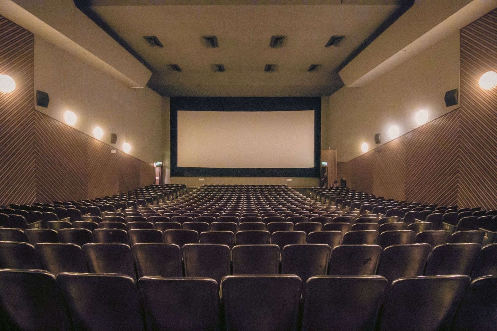 Leerer Kinosaal mit großer Leinwand und dicht angeordneten Sitzreihen
