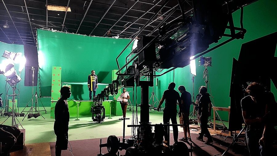 Filmstudio mit Greenscreen, Kamerakran, Scheinwerfern und Schauspielern